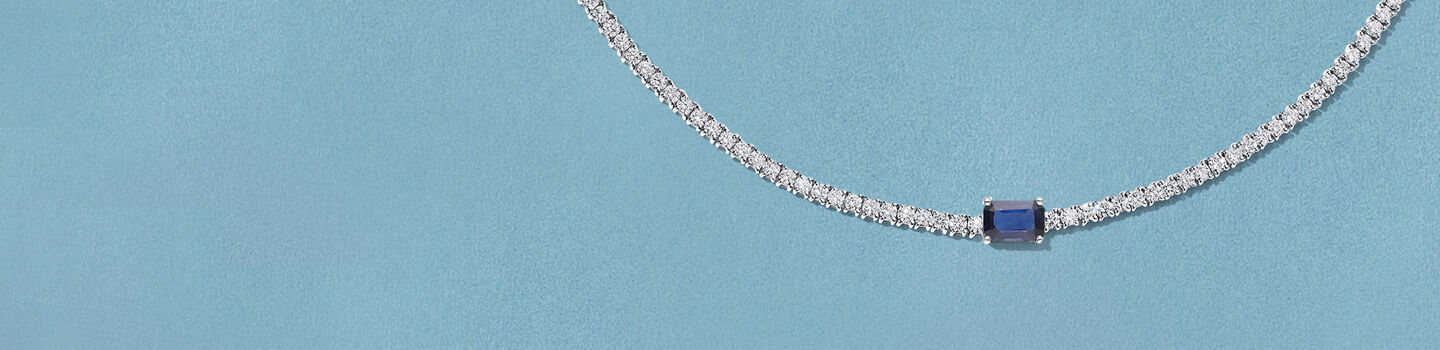 Collier Birks Essentiels avec diamants et saphir sur un fond bleu.
