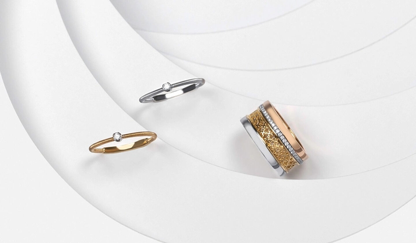 Two Marco Bicego Bi49 white and yellow gold diamond rings, beside a Birks Dare to Dream tri-gold ring