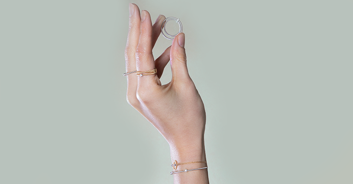 Hand holding a Marco Bicego Bi49 ring while wearing Bi49 rings and bracelets.