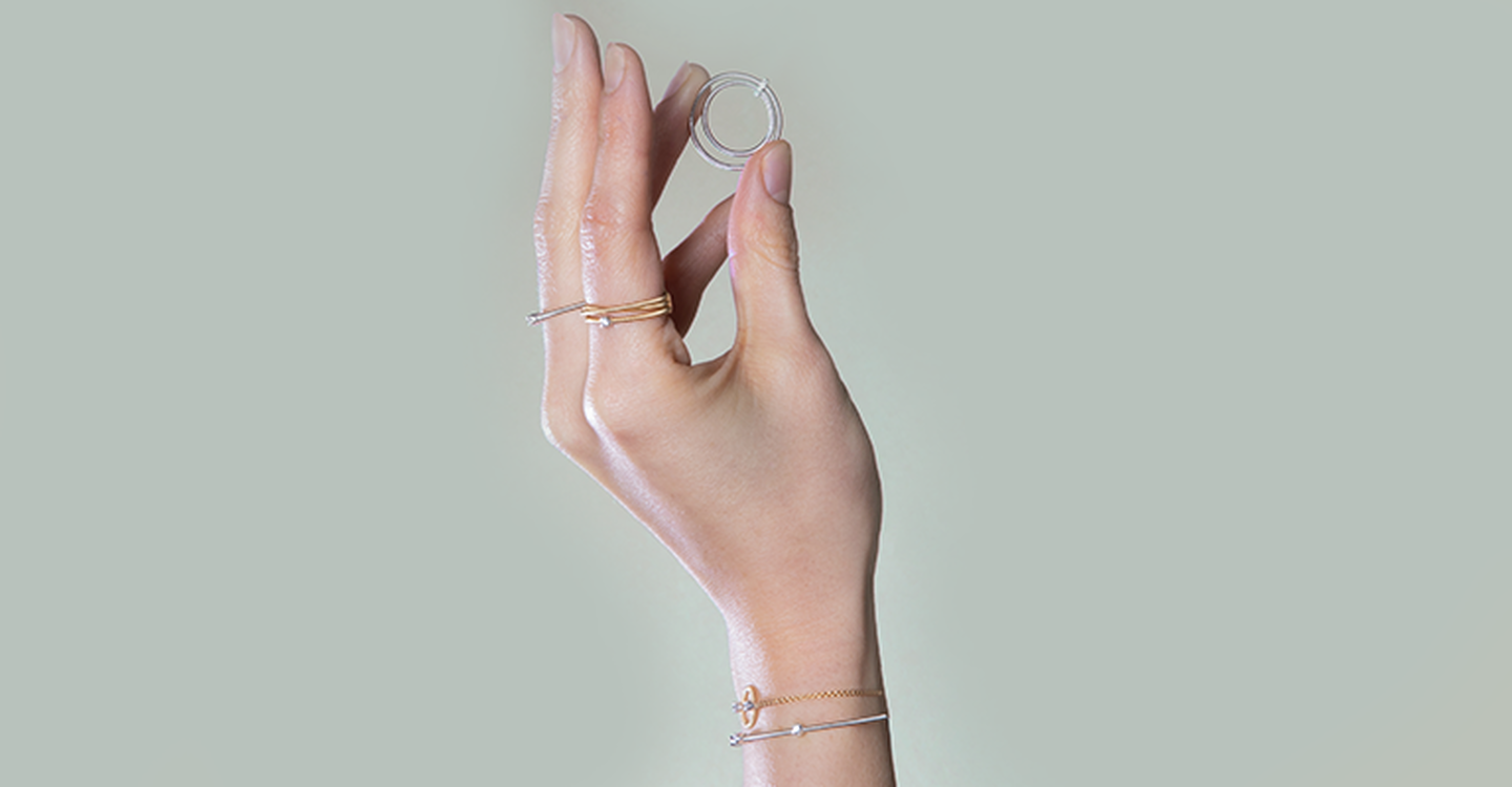 Main tenant une bague Marco Bicego Bi49 tout en portant des bagues et des bracelets Bi49.