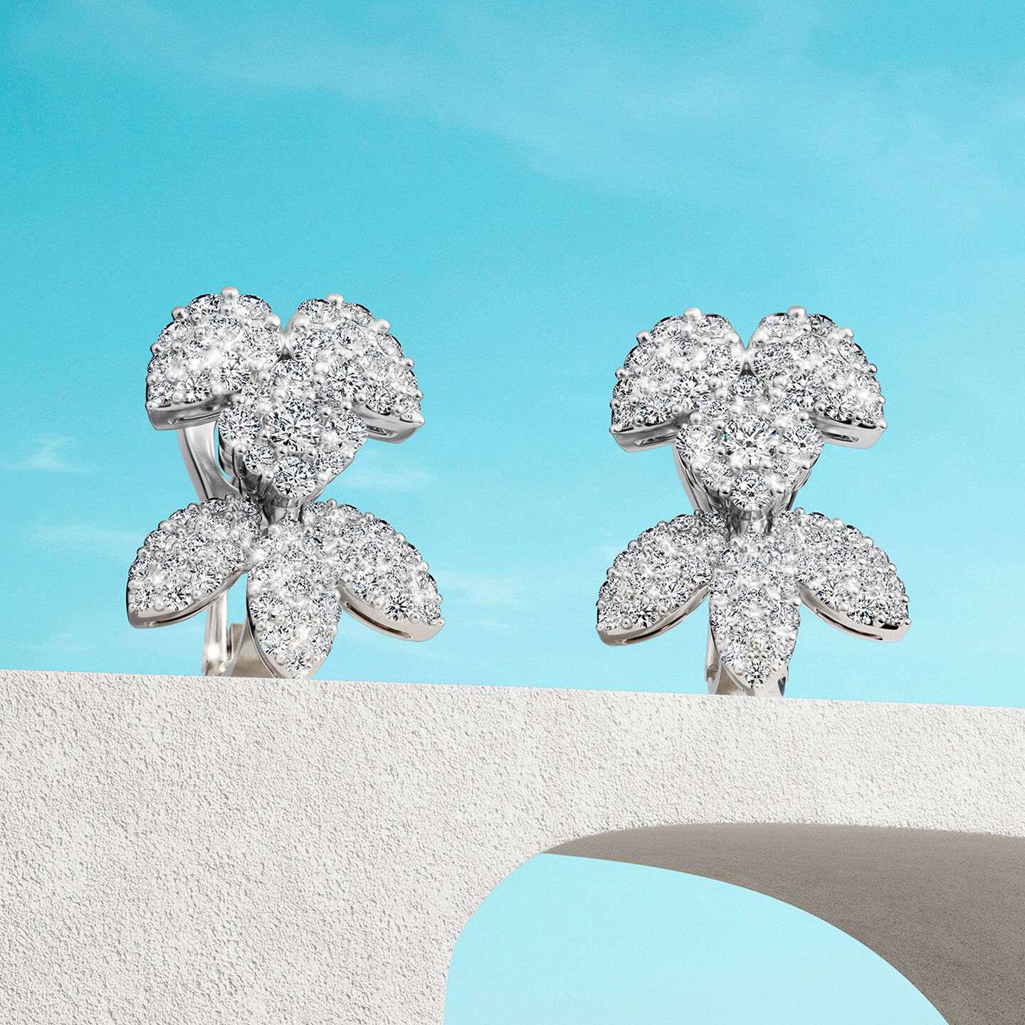 Boucles d'oreilles Birks Snowflake en diamants sur un fond bleu.