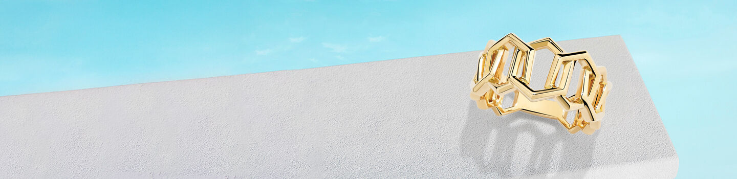 Bague Birks Bee Chic en or sur un fond bleu.