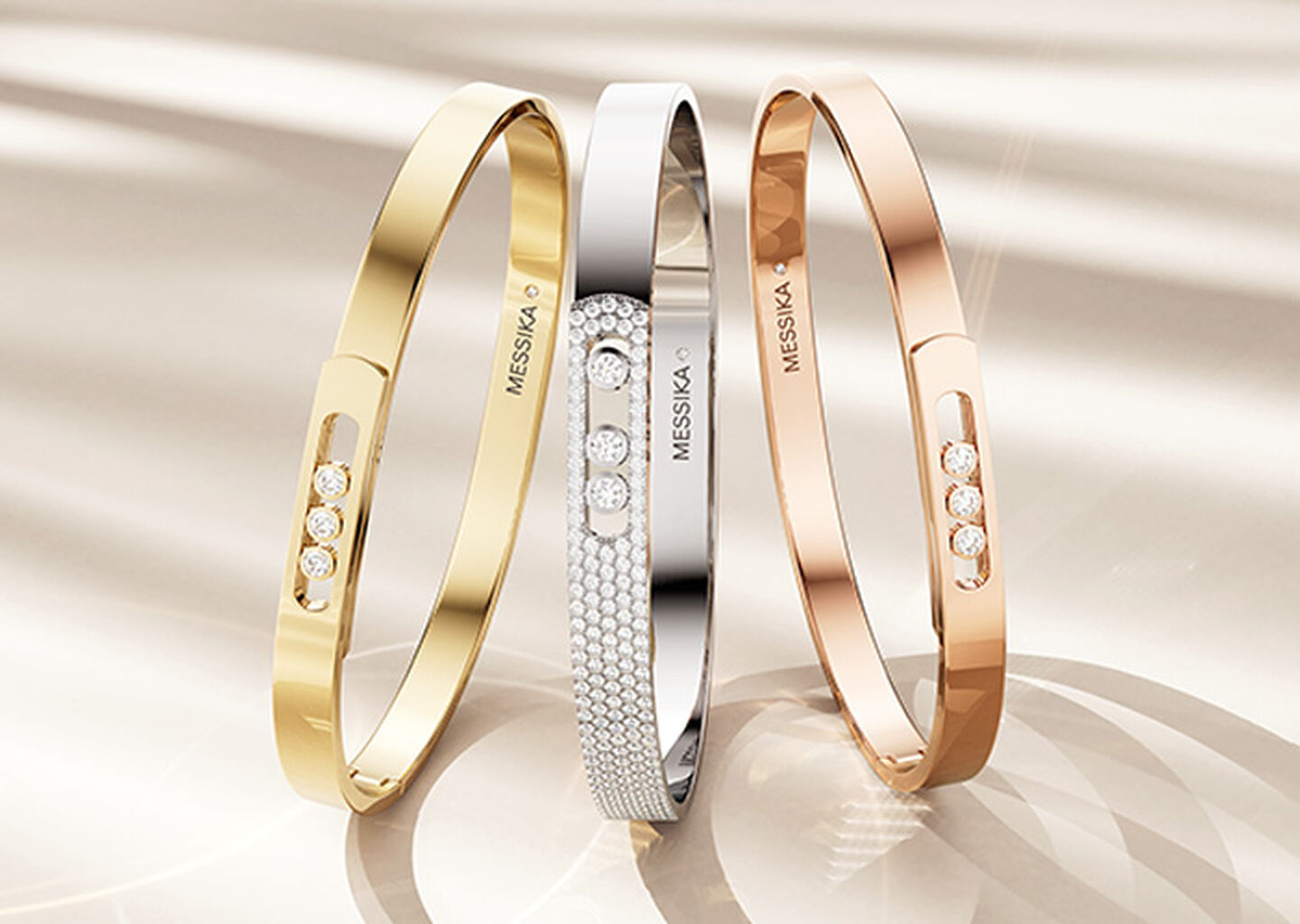 Messika Move gold and diamond bracelets on a beige background.