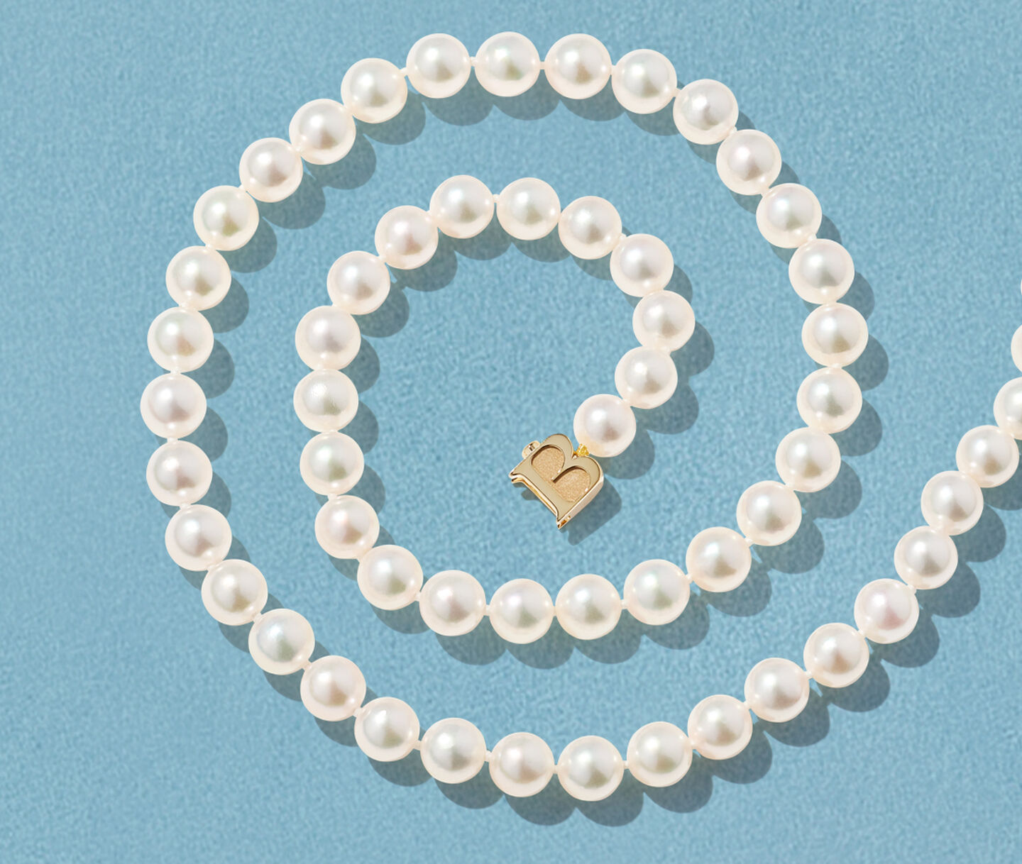 Birks Pearls Akoya necklace on a blue background.