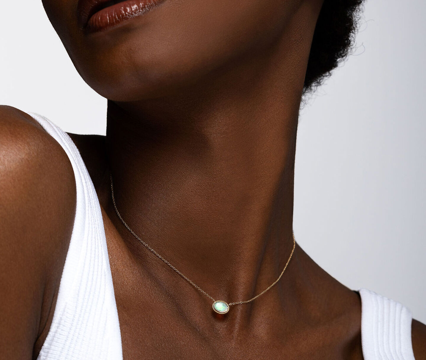 Une femme porte un collier Birks Essentiels en or jaune avec opale.