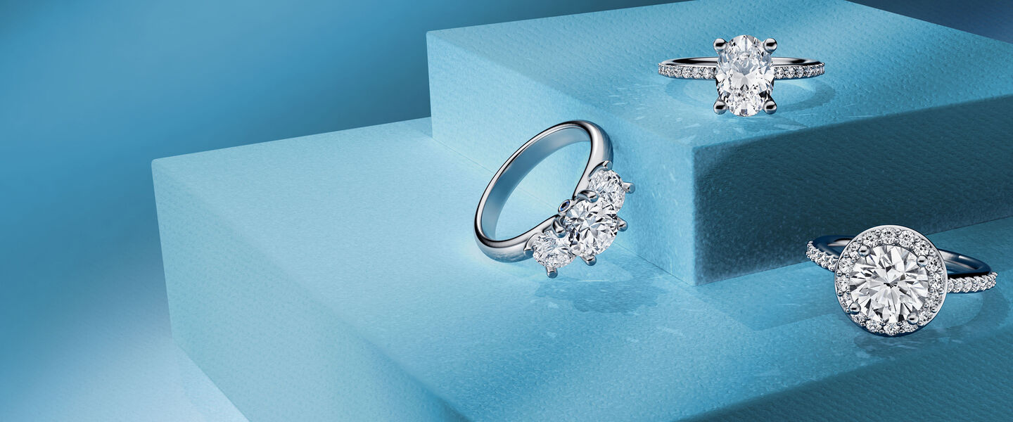 Three Birks engagement rings on a blue background.