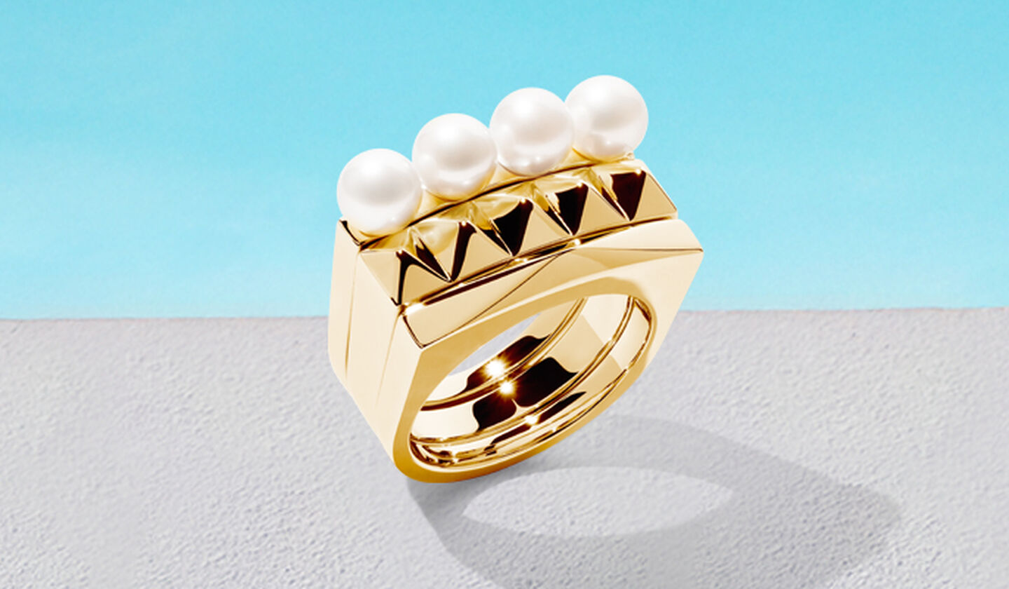 Birks Rock and Pearl gold rings on a blue background.