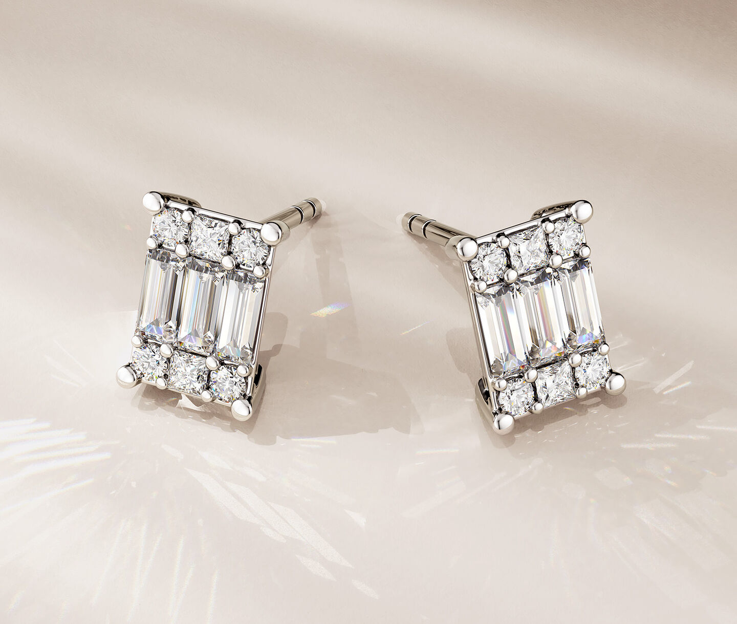 Birks Essentials diamond earrings on a beige background.
