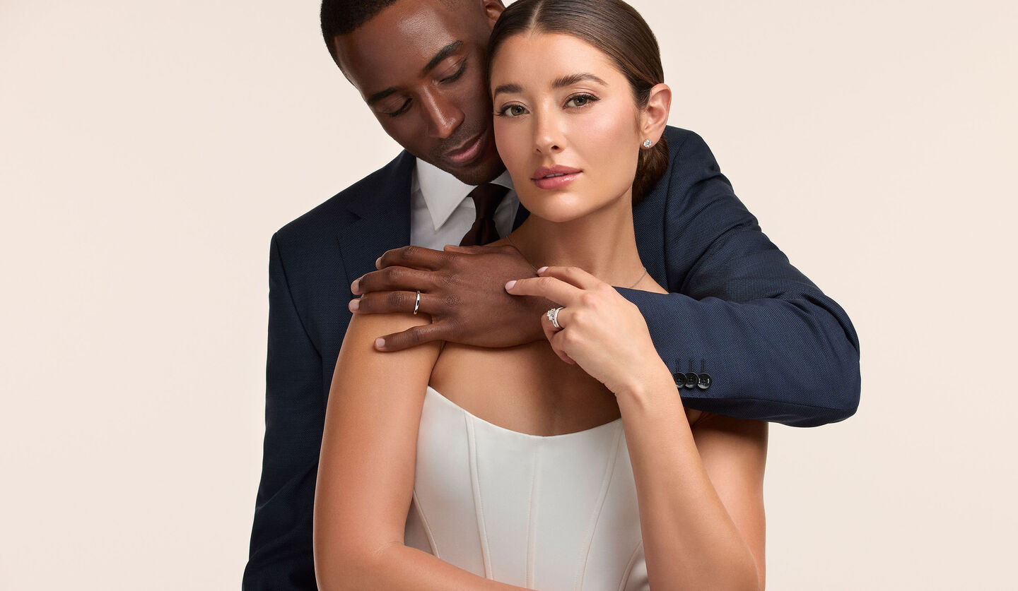 A couple embracing on their wedding day wearing Birks Bridal jewellery.