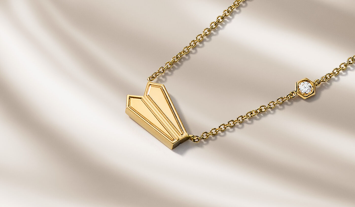 Birks Beekeeper yellow gold jewellery on a beige background.