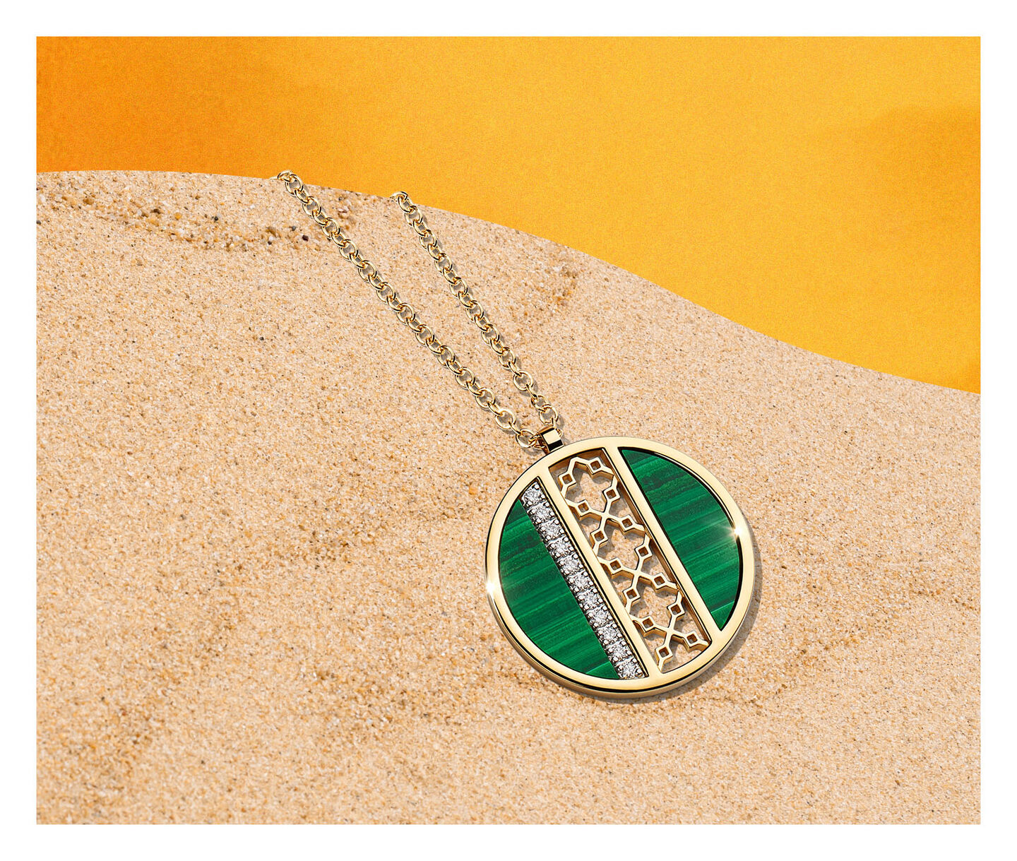 The Birks Dare to Dream&reg; Malachite and Yellow Gold Pendant on a sandy background.