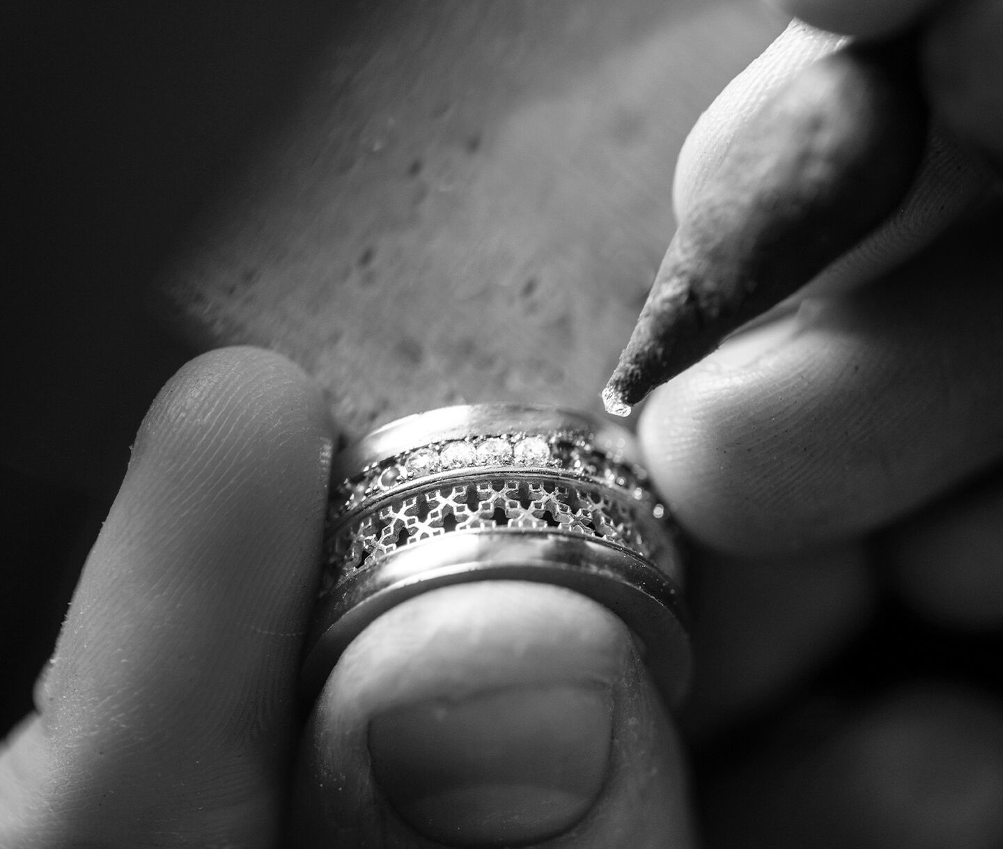 black and white photo of a jeweller placing a diamond in a ring setting.