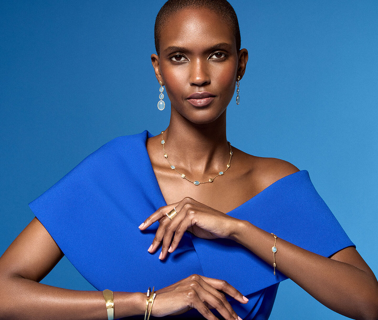 Une femme porte les bijoux Marco Bicego sur un fond bleu.