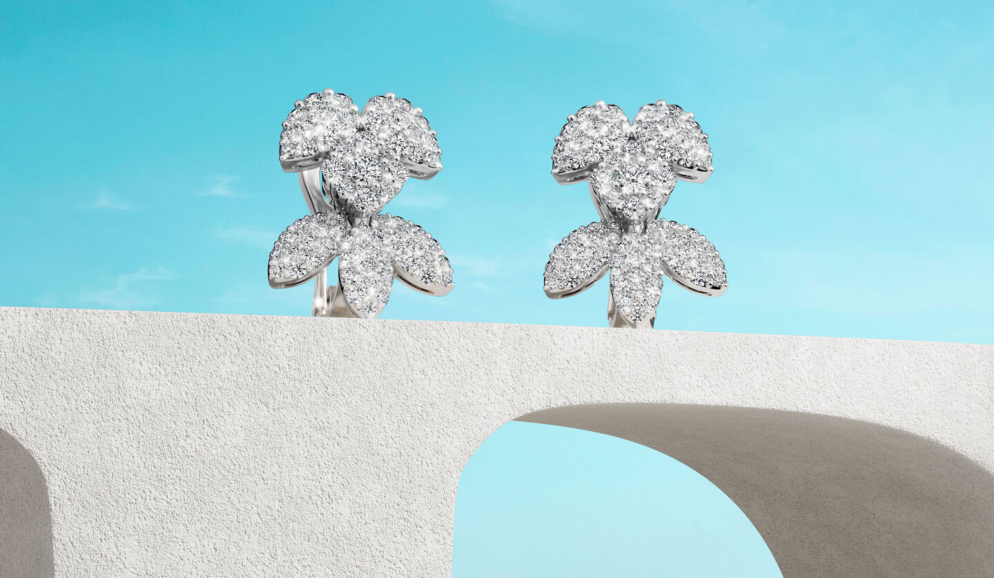 Birks Snowflake diamond earrings on a blue background.