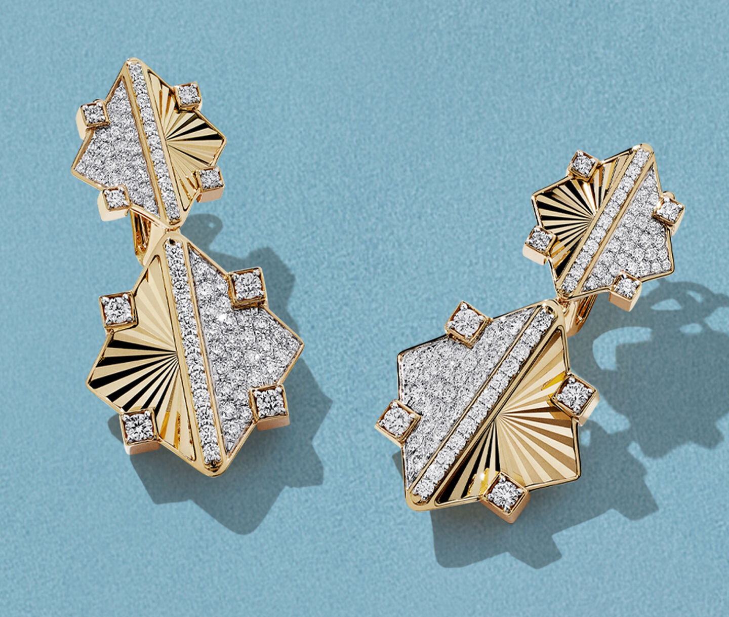 Boucle d'oreilles Birks Muse en or jaune avec diamants sur un fond bleu.