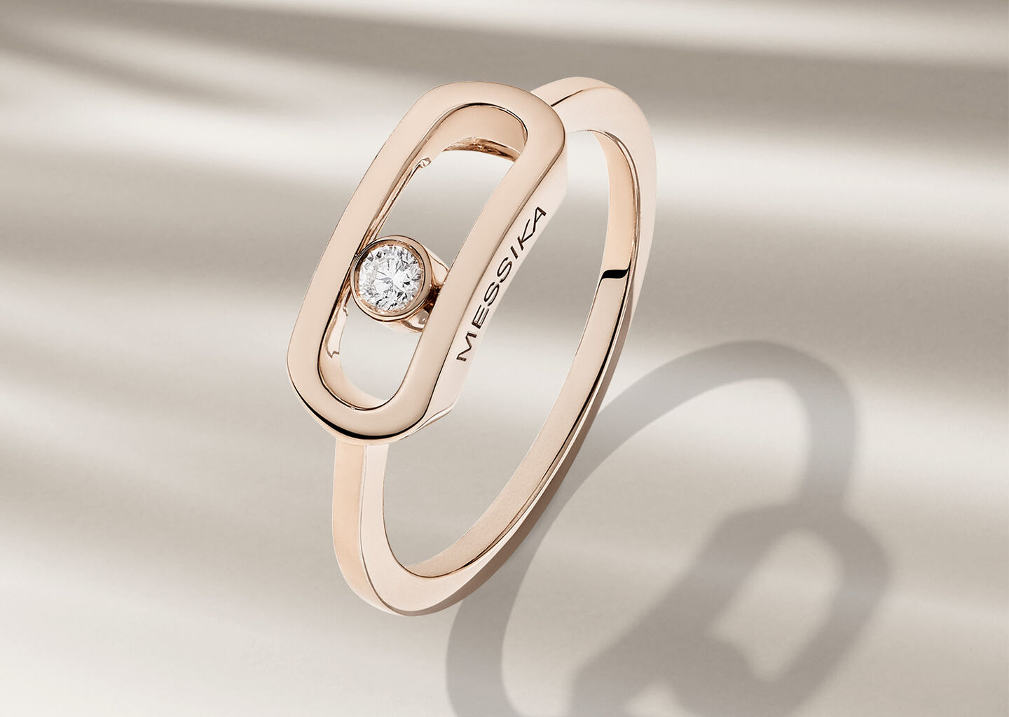Messika Move Noa rose gold and diamond ring on a beige background.