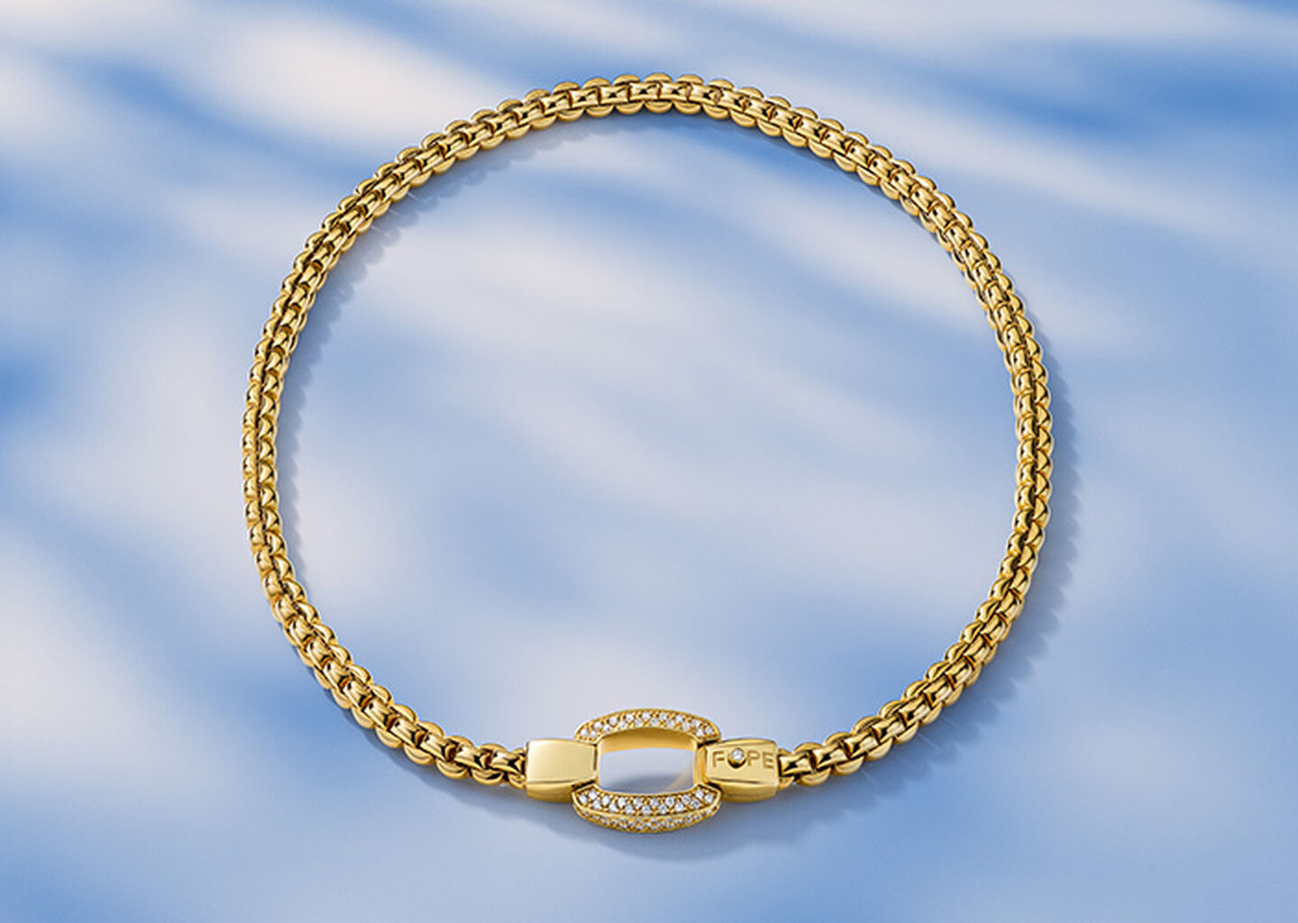 FOPE Eka yellow gold clasp necklace on a blue background.