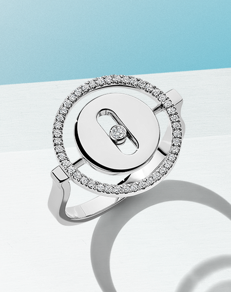 Bague Messika Lucky Move avec diamants sur un fond bleu.