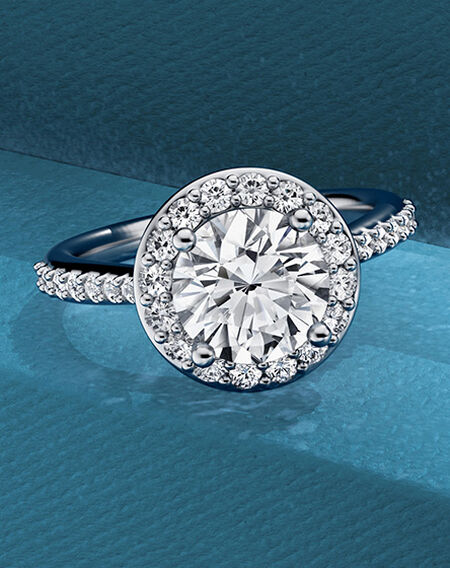 Bague de fian&ccedil;ailles avec halo Birks 1879 sur un fond bleu.