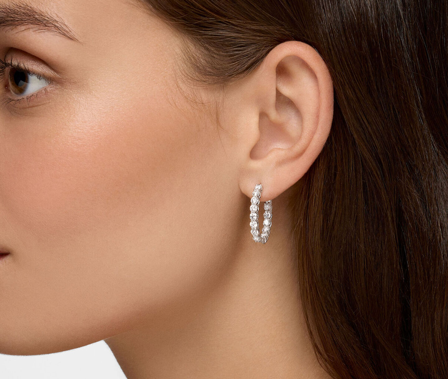Une femme porte les boucles d'oreilles en diamants Birks Essentiels.