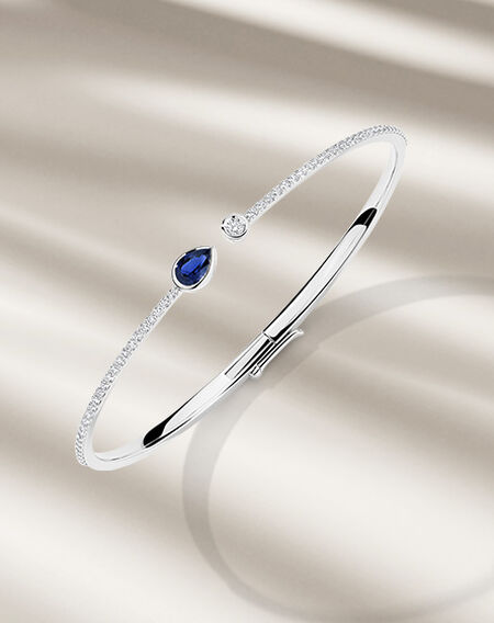 Birks Splash sapphire and diamond bangle bracelet on a beige background.