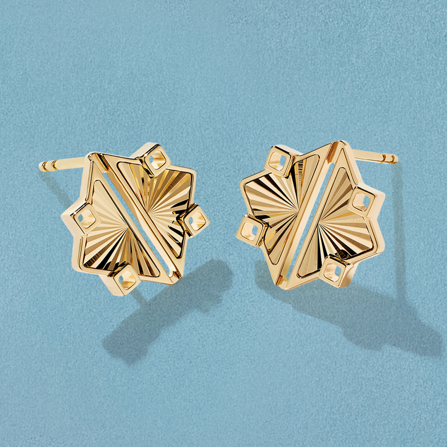 Boucles d'oreilles en or jaune Birks Muse sur un fond bleu.