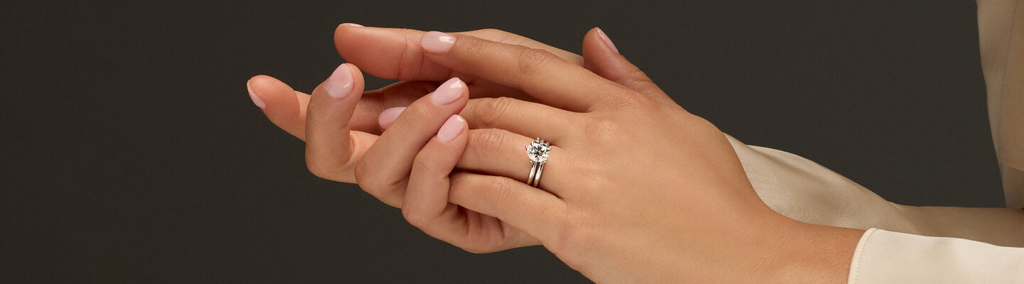 A woman wearing a Birks bridal engagement ring.