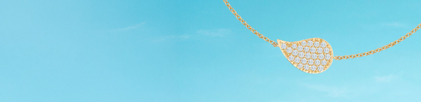 Birks Pétale diamond yellow gold necklace on a blue background.
