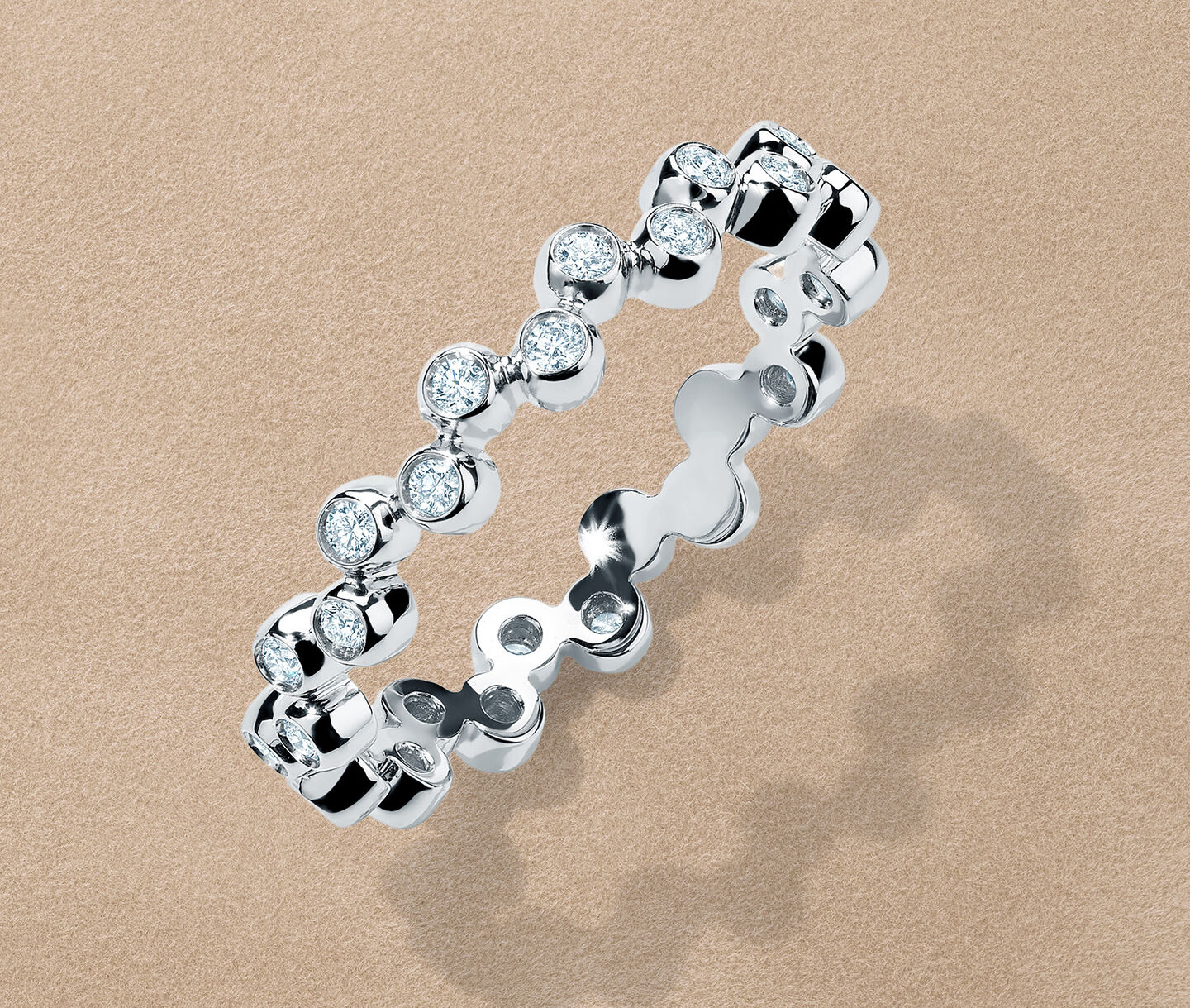 Birks Iconic Splash diamond and white gold stackable ring on a brown background.