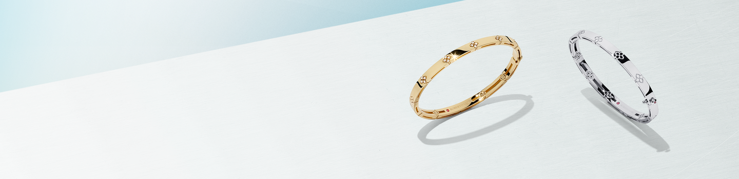 Roberto Coin yellow gold bangle on orange pyramid and blue sky.