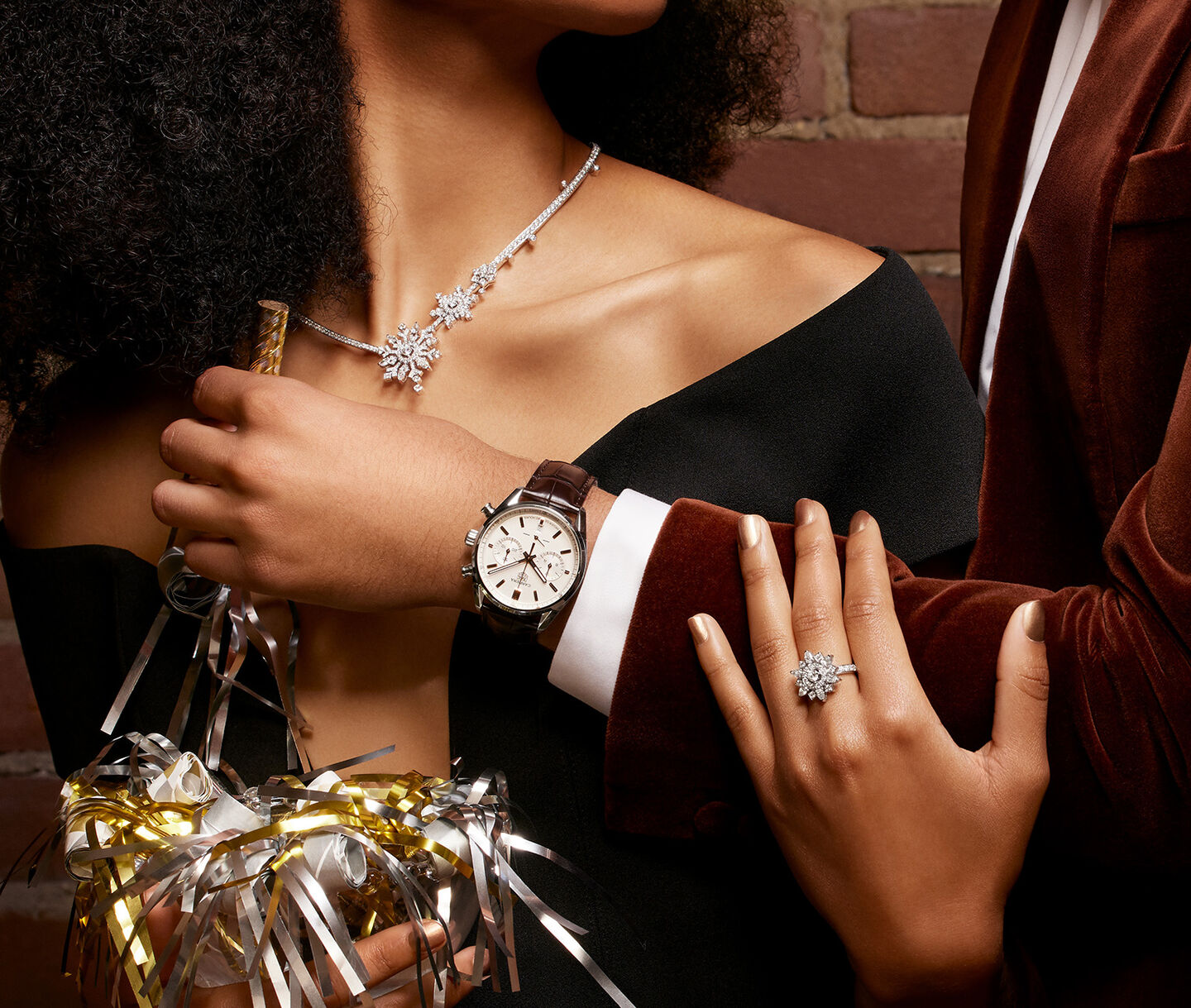 A man and woman dressed for the holiday season in Maison Birks jewellery and watches.