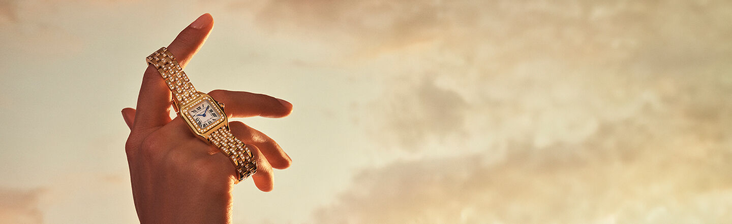 A woman holding a Panthere de Cartier watch.