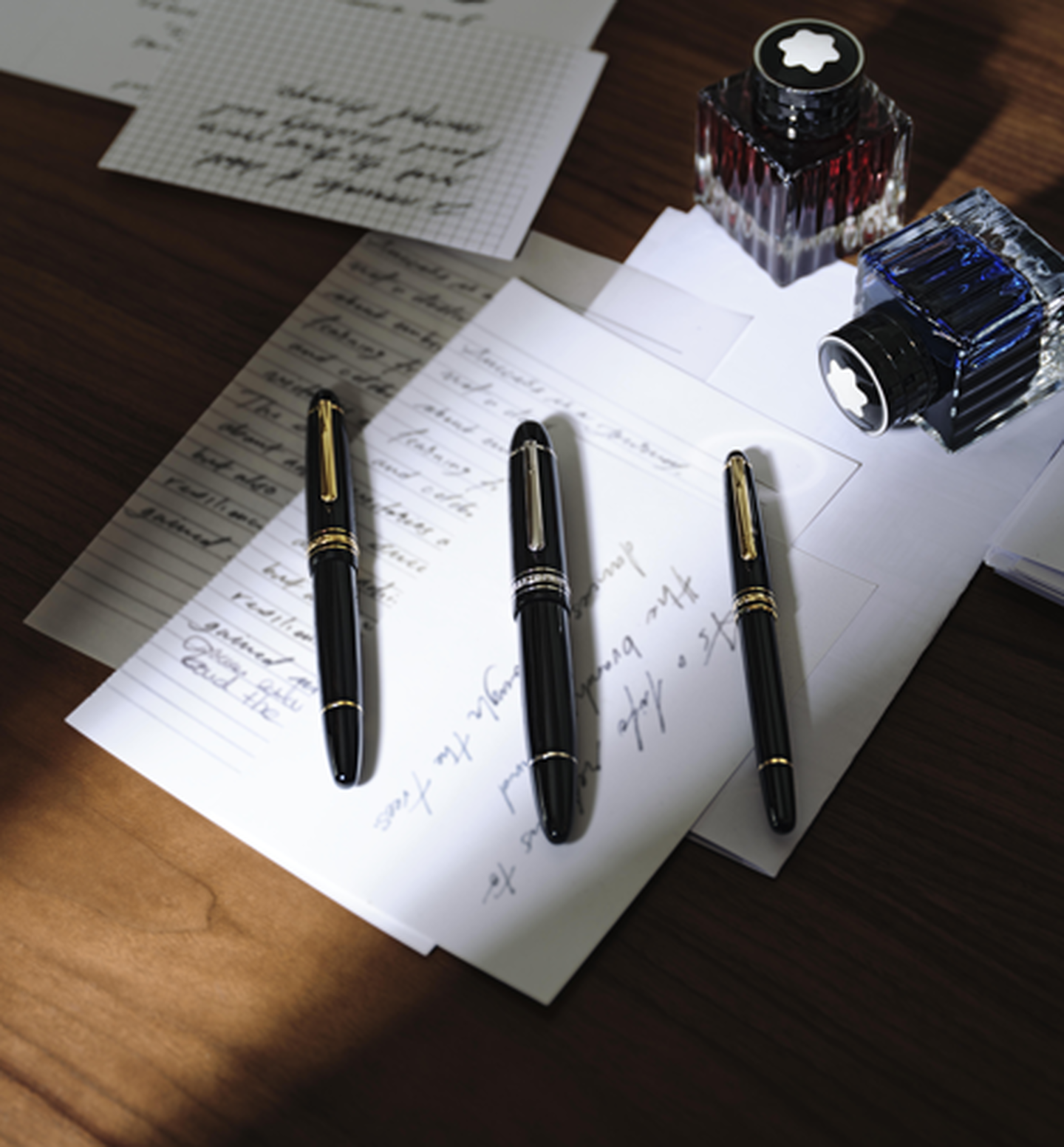 Three Montblanc pens on a desk.
