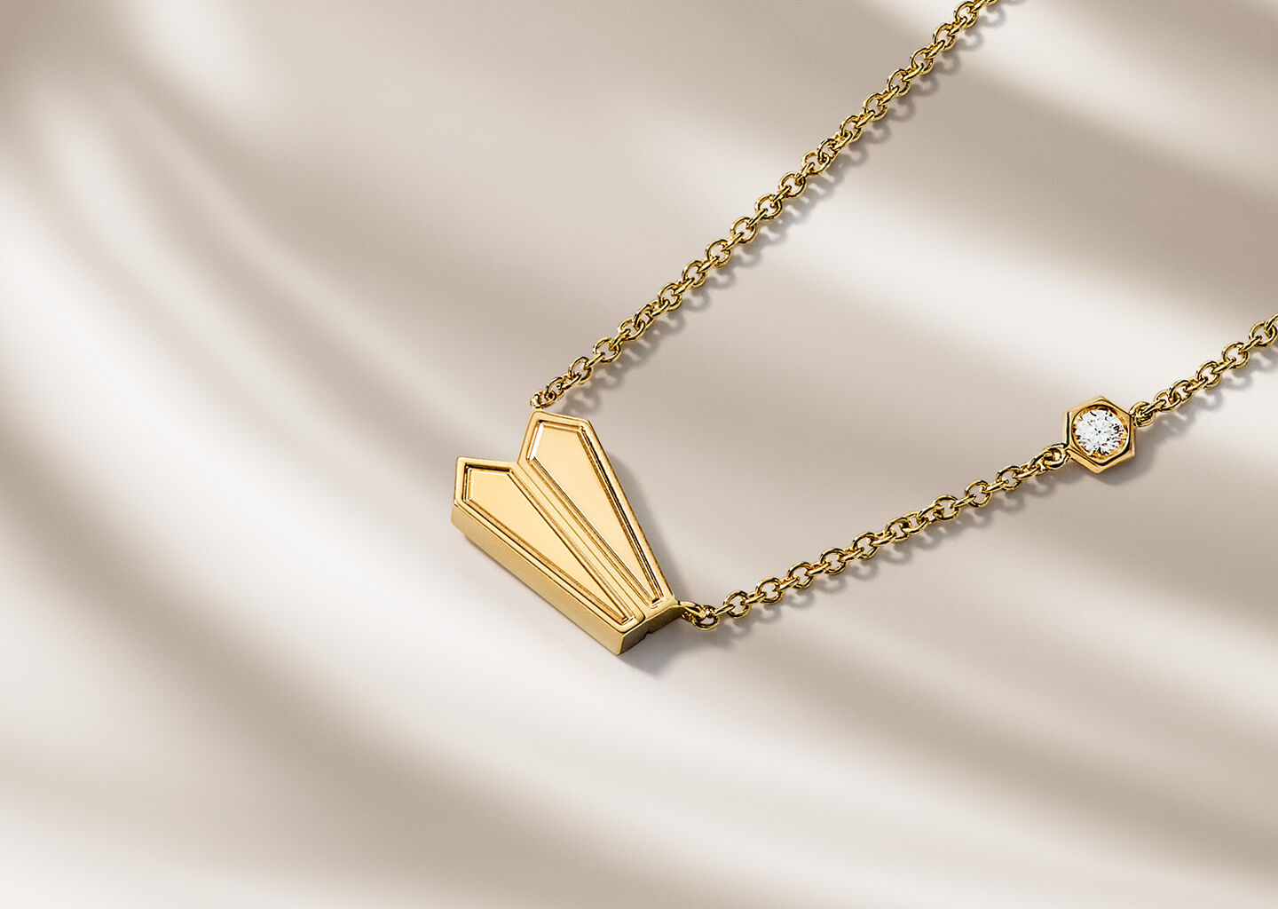 Birks Beekeeper yellow gold necklace on a beige background.