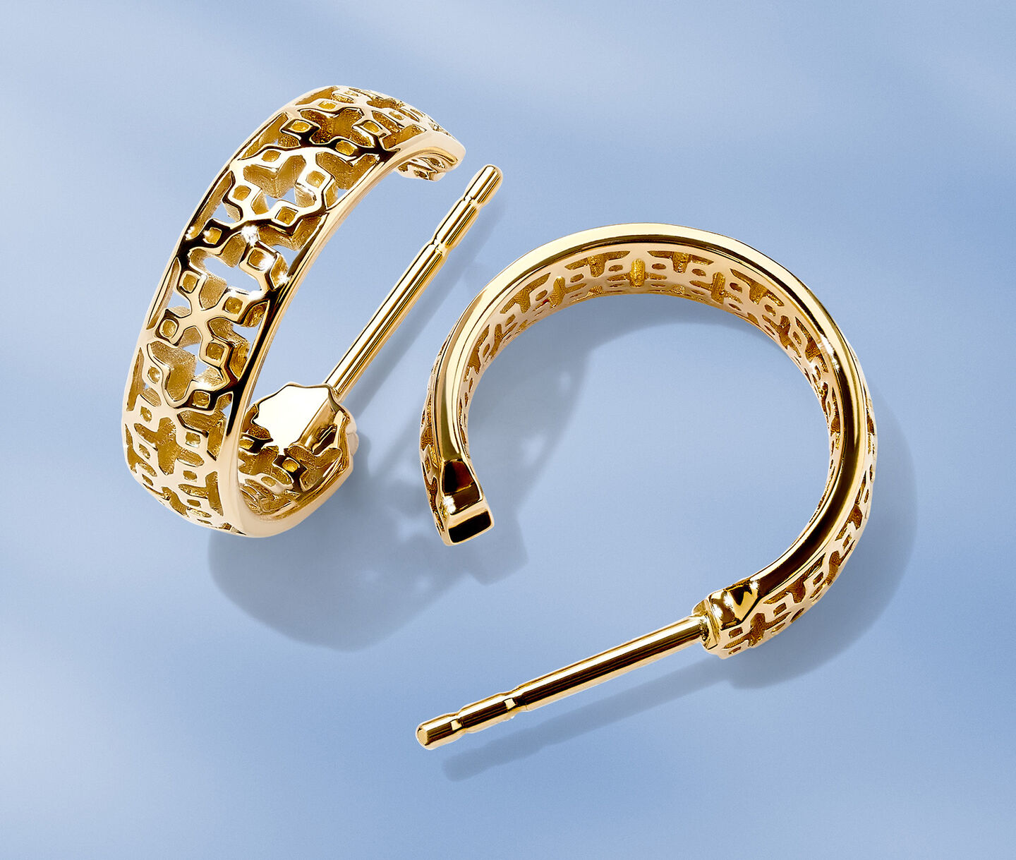 Birks Dare to Dream yellow gold earrings on a blue background.