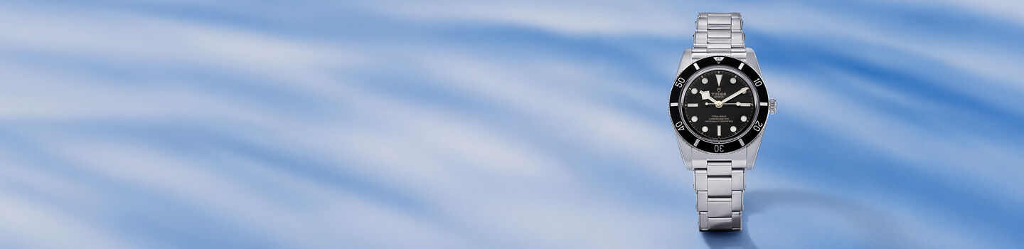 TUDOR men's watch on a blue background.