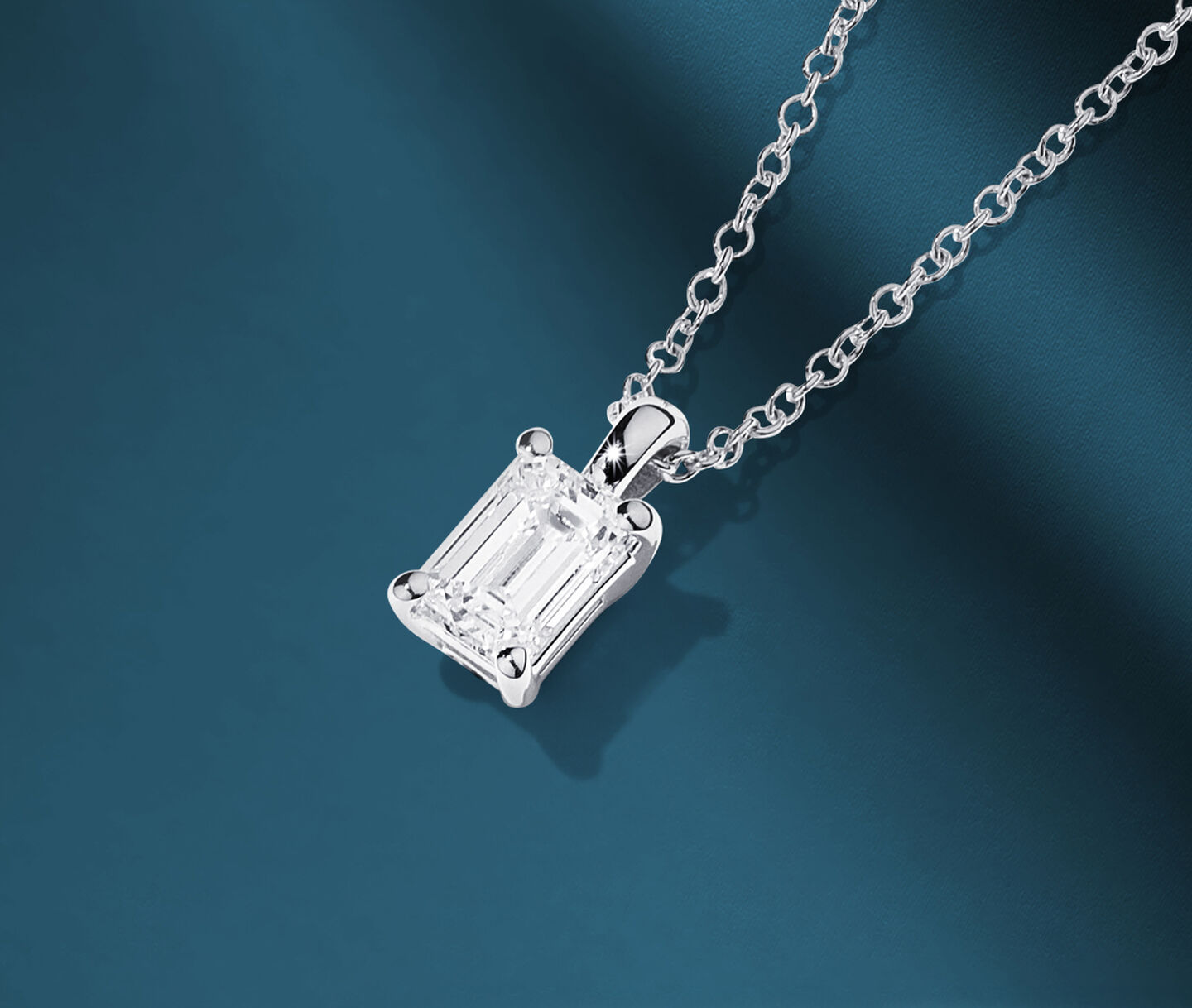 Birks Blue emerald-cut diamond solitaire pendant on a blue background.