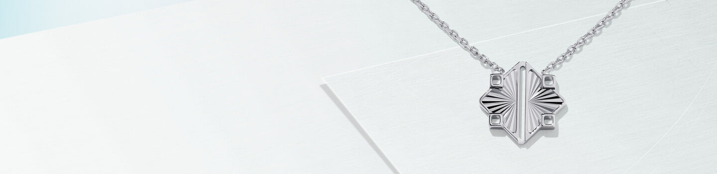 Birks Muse silver pendant necklace on a light blue background.