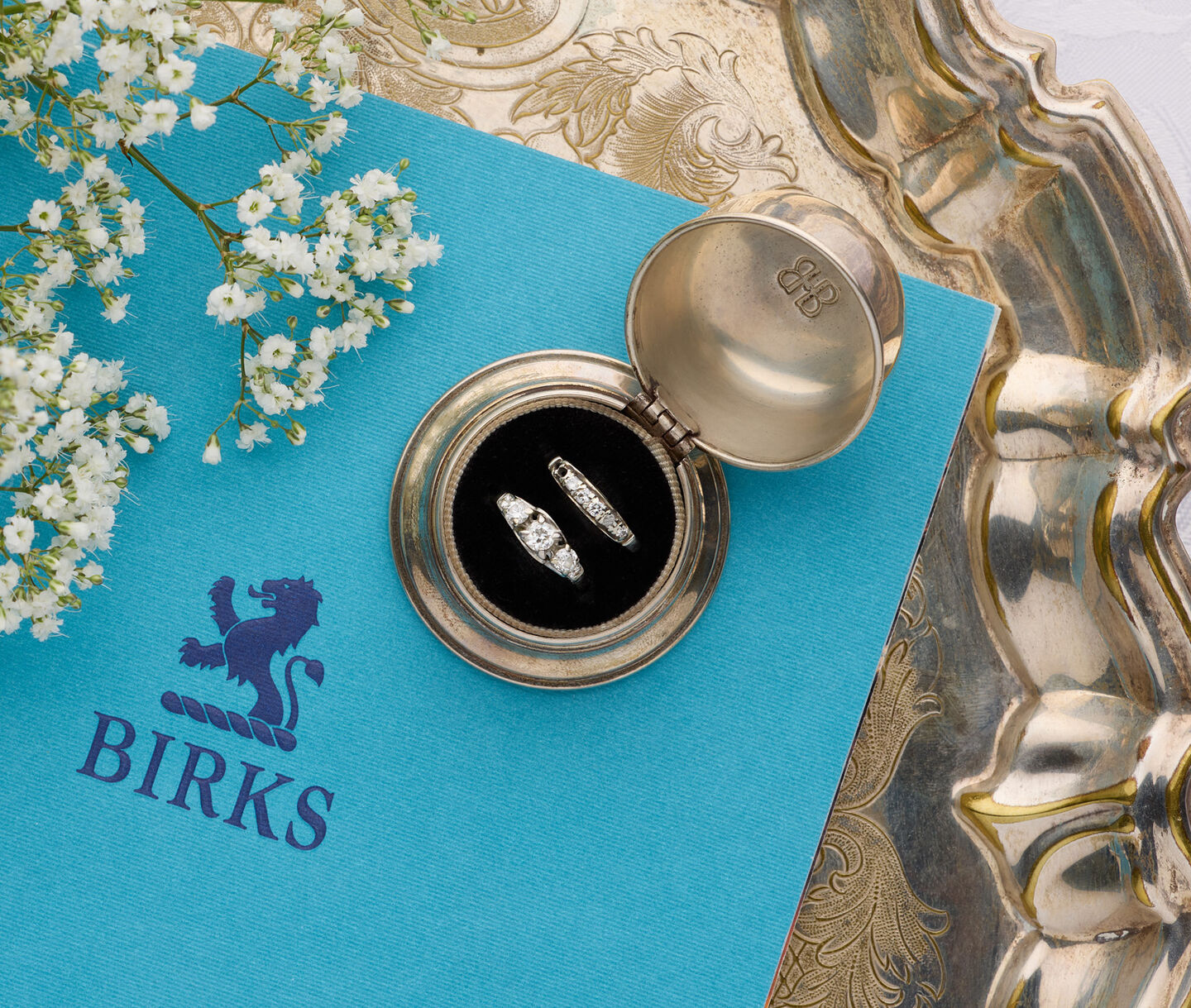 Heirloom diamond rings in a vintage keepsake box atop a Birks book, representing love passed through generations.