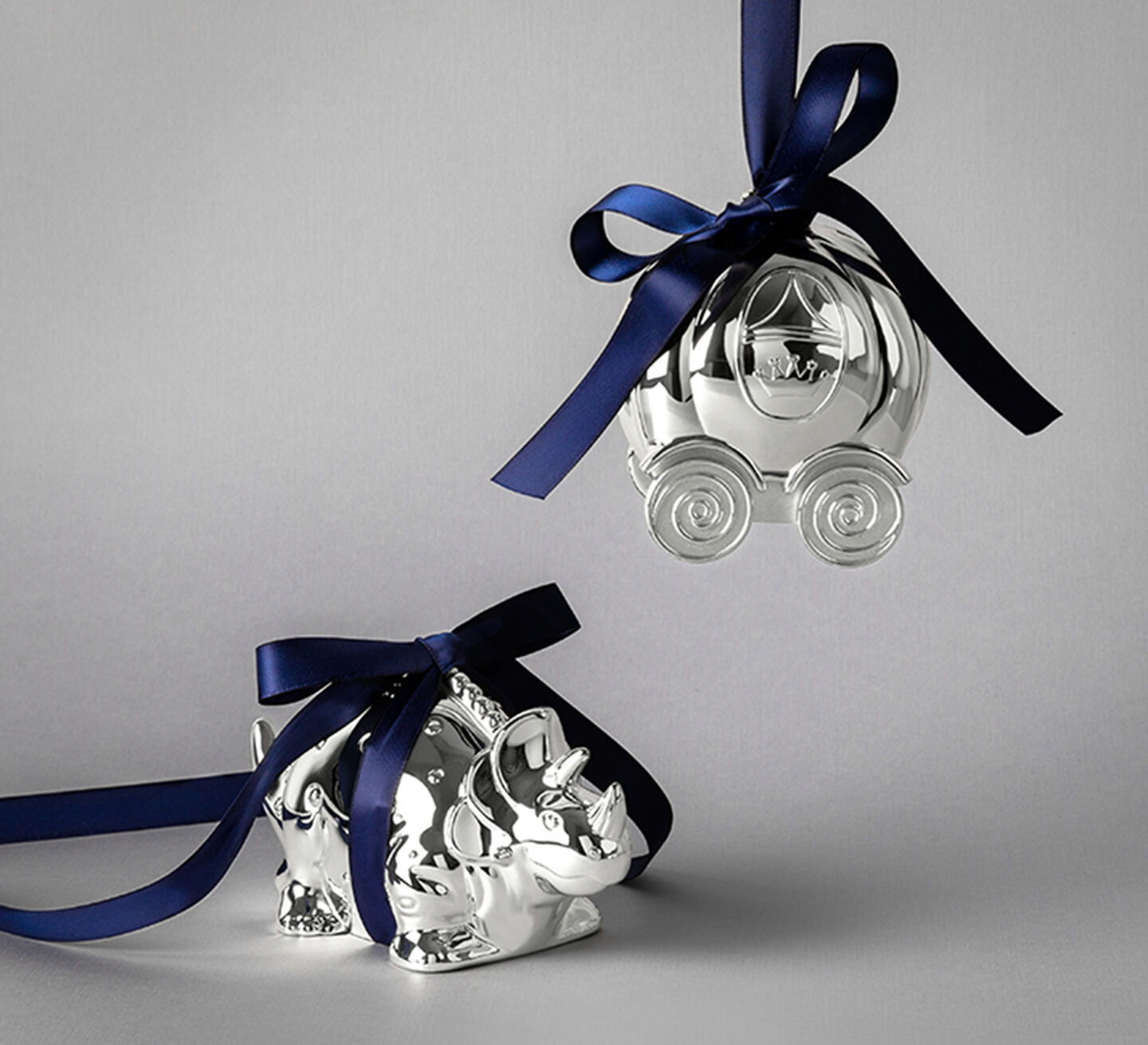 A silver triceratops and a pumpkin carriage both wrapped in blue ribbon