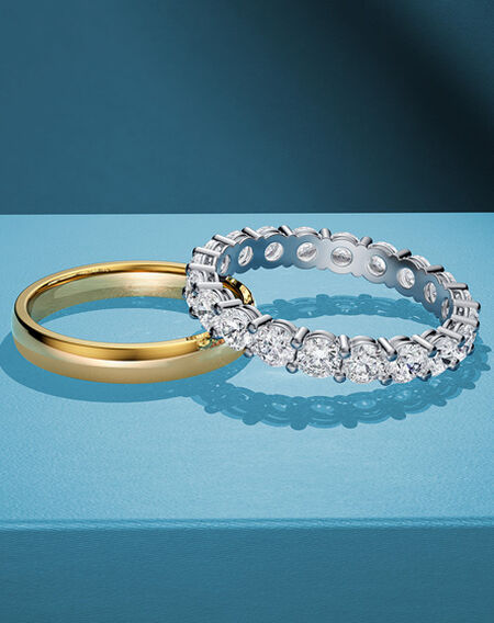 An assortment of women's wedding bands from Birks on a blue background.