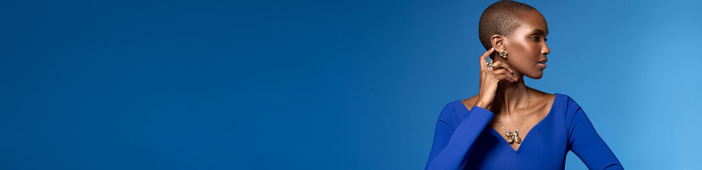 A woman wearing Pasquale Bruni's Giardini Segreti jewellery collection on a blue background.