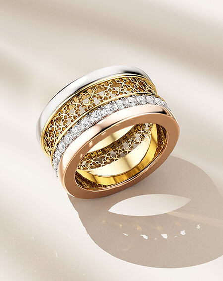 Birks Dare to Dream tri-gold and diamond ring on a beige background.