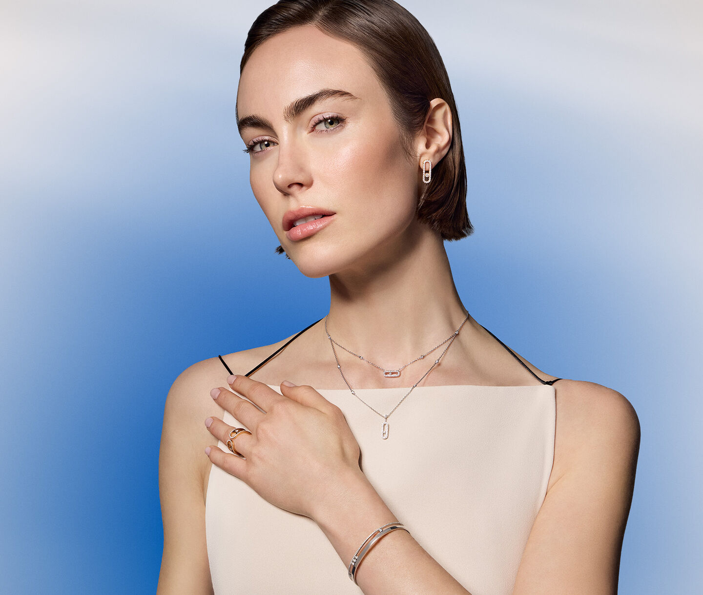 A woman wearing Messika diamond jewellery on a blue background.