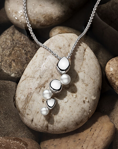 Birks Pebble necklace on a flat grey pebble background.