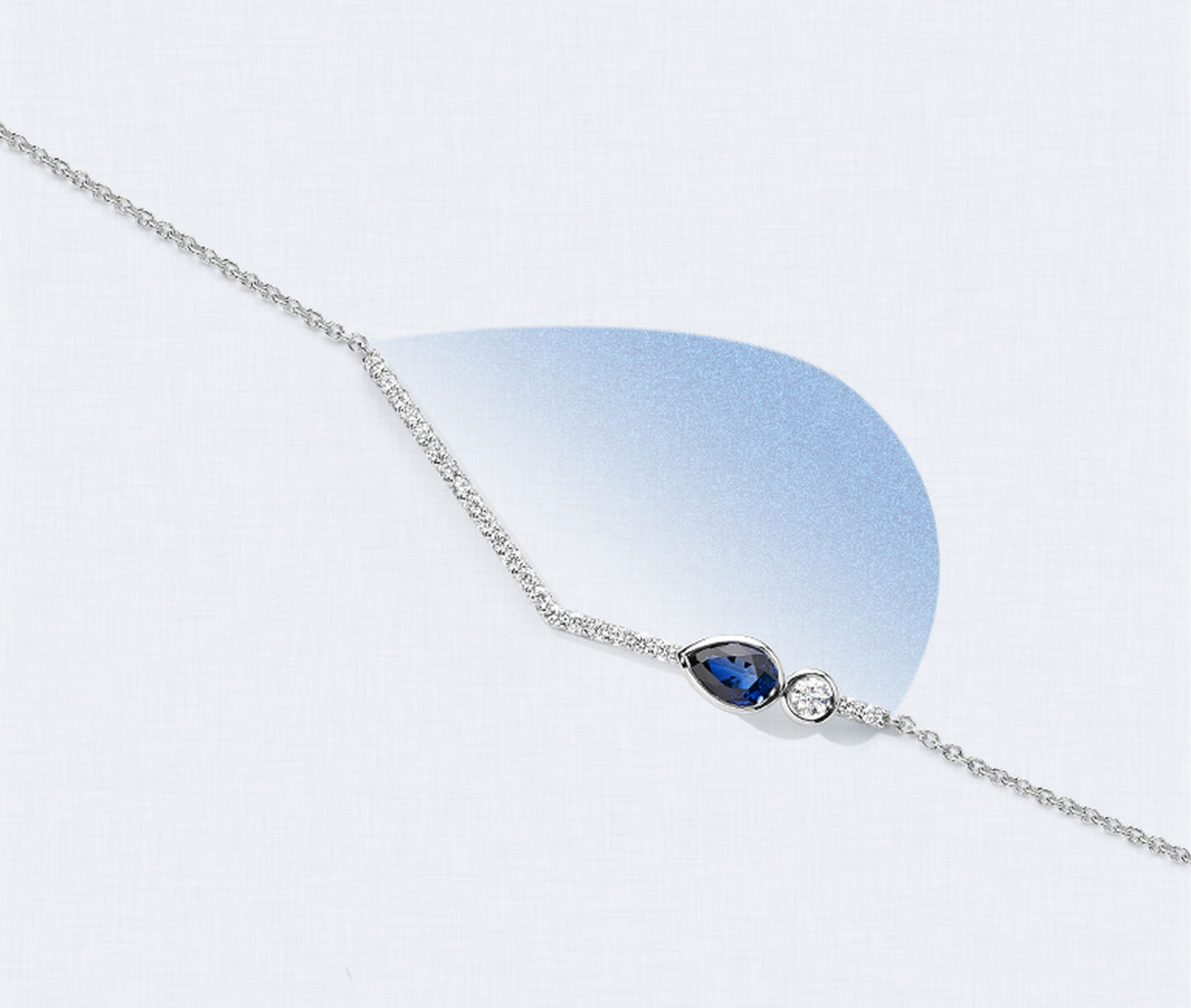 A blue sapphire and a row of diamonds on a white gold necklace