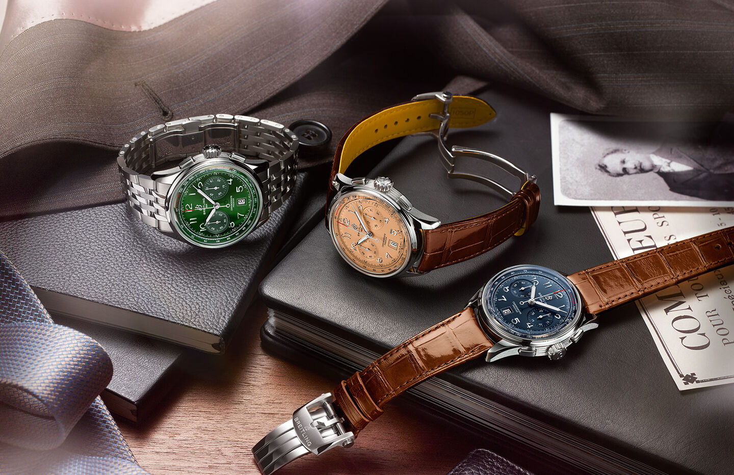 Three Breitling watches sit atop of a pile of leather-bound notebooks