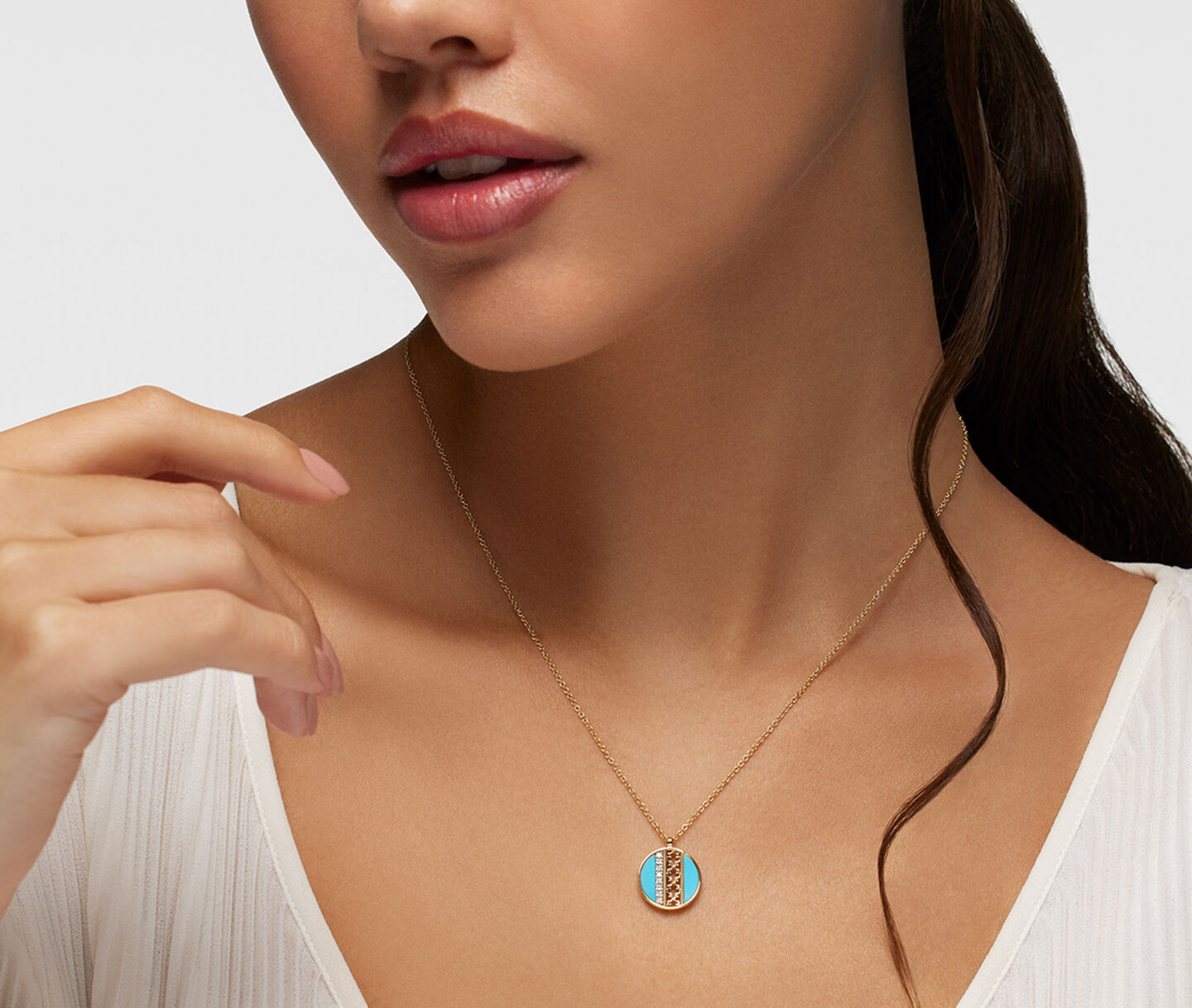 A woman wearing a Birks Dare to Dream turquoise medallion necklace.