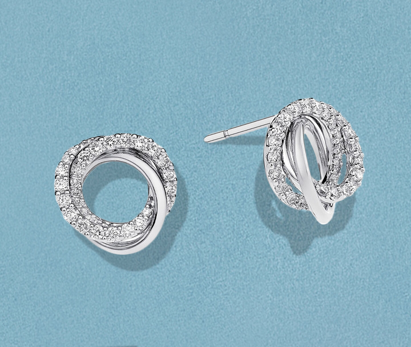 Birks Rosee du Matin gold circle earrings on a blue background.
