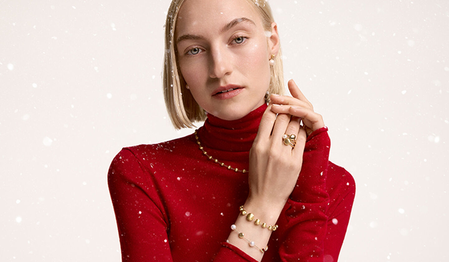 Une femme porte les bijoux en or jaune avec perles de Maison Birks.